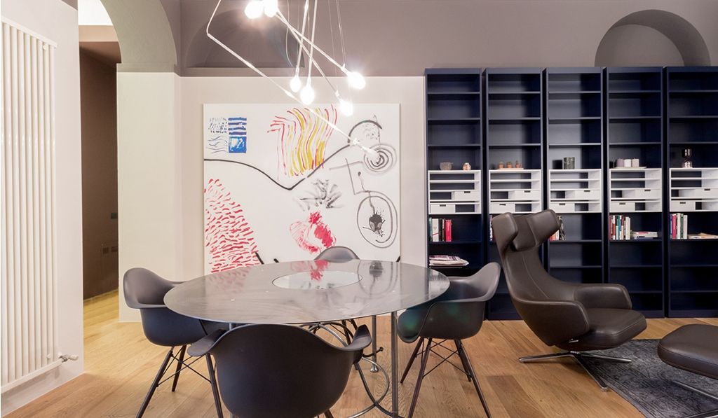 <p>Soggiorno arredato da SM arredamenti, librerie Rialto Collezione Simon di Cassina, poltrona Grand Repos e sedie Eames plastic chair DAW di Vitra, tavolo tondo in ferro Lem e quadri Botturi.</p>